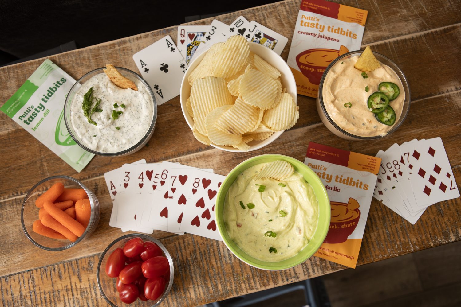 Four Tasty Tidbits dips on a game night table with chips and vegetables